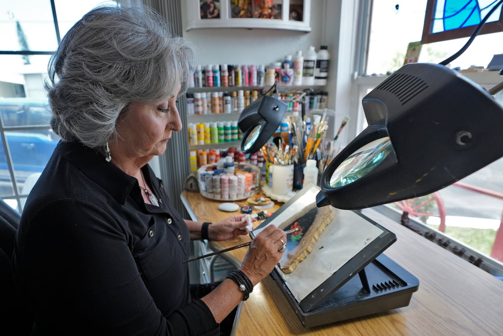 Artist Lora Duguay paints on a stone from her wheelchair at home in Clearwater, Fla., on Tuesday, June 10, 2025. (AP Photo/Chris O'Meara)
