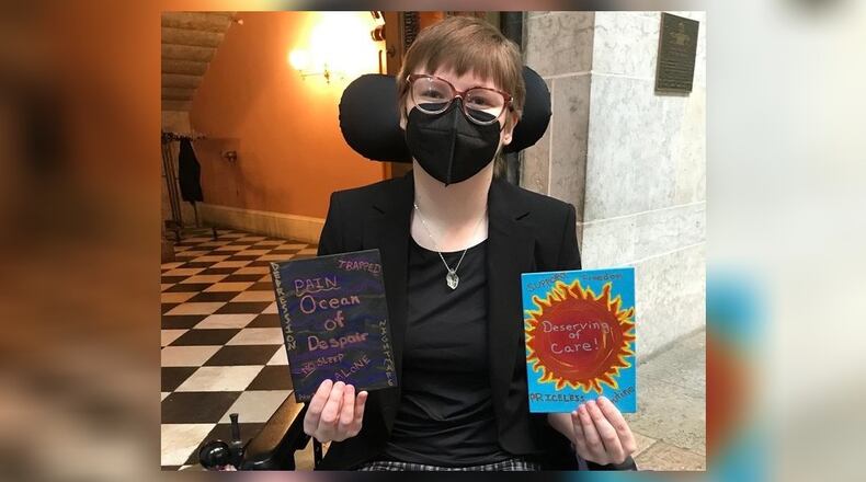 Georgie Elson stands with art they created in a Creative Changemakers workshop: one representing life without personal care aides and the other with having care aides. These paintings were used to create postcards that were sent out to area lawmakers. CONTRIBUTED