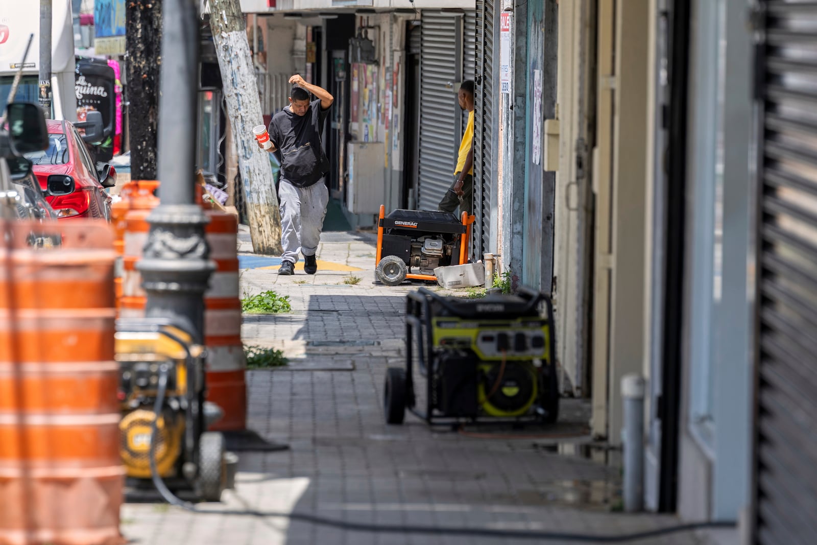Generators line the sidewalk of a commercial street in Barrio Obrero as shops try to remain open during a prolonged power outage in San Juan, Puerto Rico, Thursday, April 17, 2025. (AP Photo/Alejandro Granadillo)