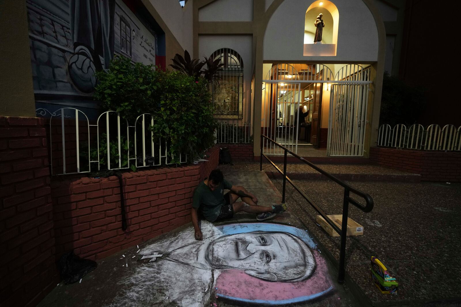 An artist paints an image of the late Pope Francis outside San Antonio parish before a Mass by fans of San Lorenzo soccer club, of which the pontiff was a lifelong supporter, in Buenos Aires, Argentina, Wednesday, April 23, 2025. (AP Photo/Natacha Pisarenko)