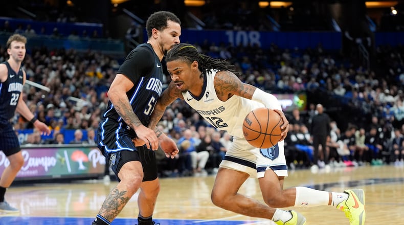 Memphis Grizzlies guard Ja Morant (12) drives around Orlando Magic guard Cole Anthony, left, during the second half of an NBA basketball game, Friday, Feb. 21, 2025, in Orlando, Fla. (AP Photo/John Raoux)
