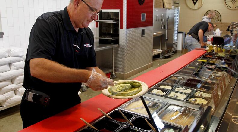 Ray Wiley creates a pizza at his recently opened restaurant Rapid Fired Pizza in Washington Twp. Customers order custom made pizza in a serving line similiar to Chipotle in the new “fast-casual” chain.