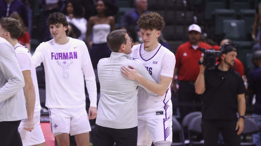 Centerville graduate Tom House (right), a senior at Furman, hugs assistant coach Pat Estepp, a former head coach at Cedarville, after a victory against Richmond in the first round of the ESPN Events Invitational on Thursday, Nov. 27, 2025, at the State Farm Field House in Kissimmee, Fla. David Jablonski/Staff