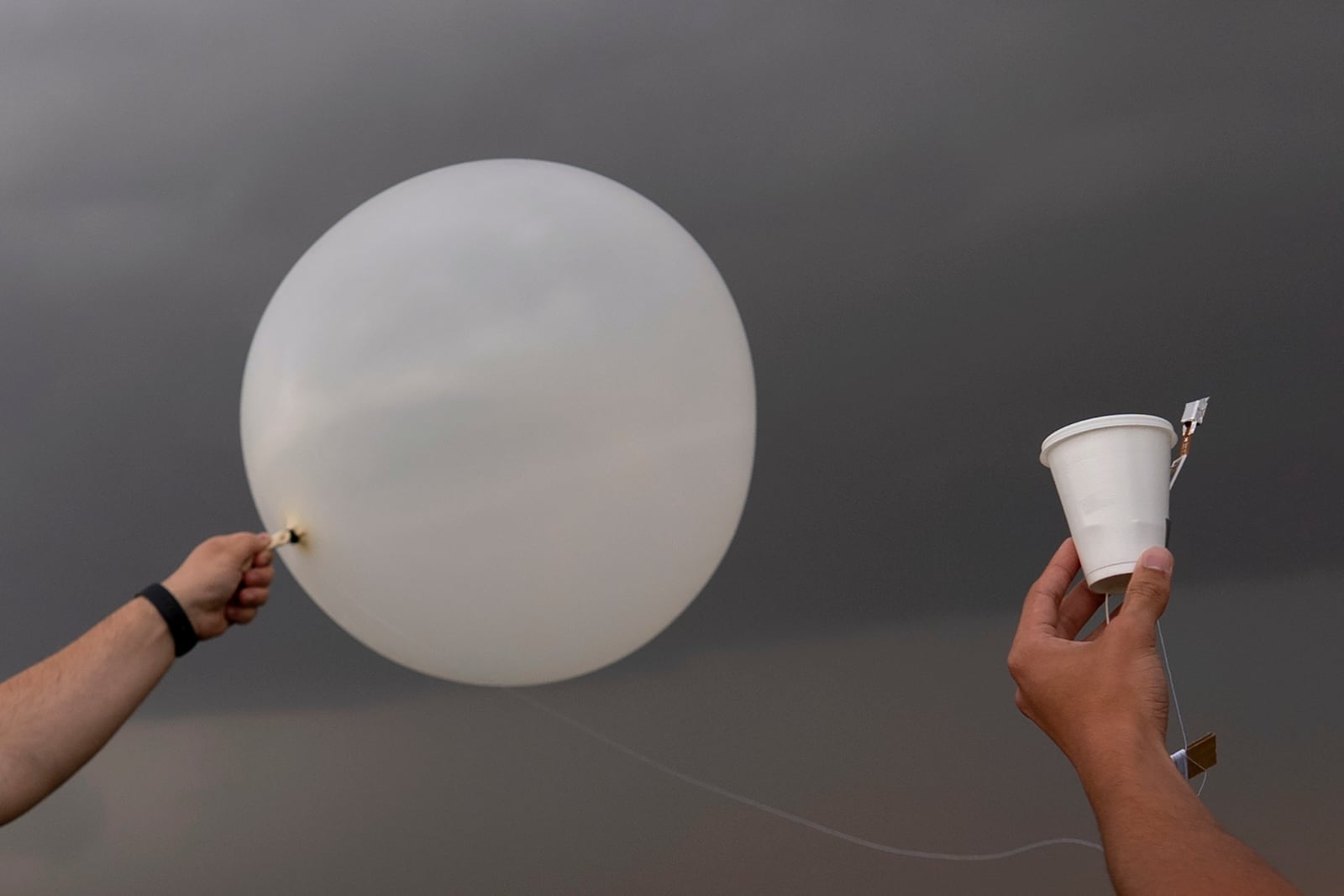 Red team and Project ICECHIP members Wyatt Ficek, left, and Ethan Mok, right, release a latex weather balloon with an attached instrument called a windsond into the inflow region of a storm to collect data during a Project ICECHIP operation Thursday, June 5, 2025, near Morton, Texas. (AP Photo/Carolyn Kaster)