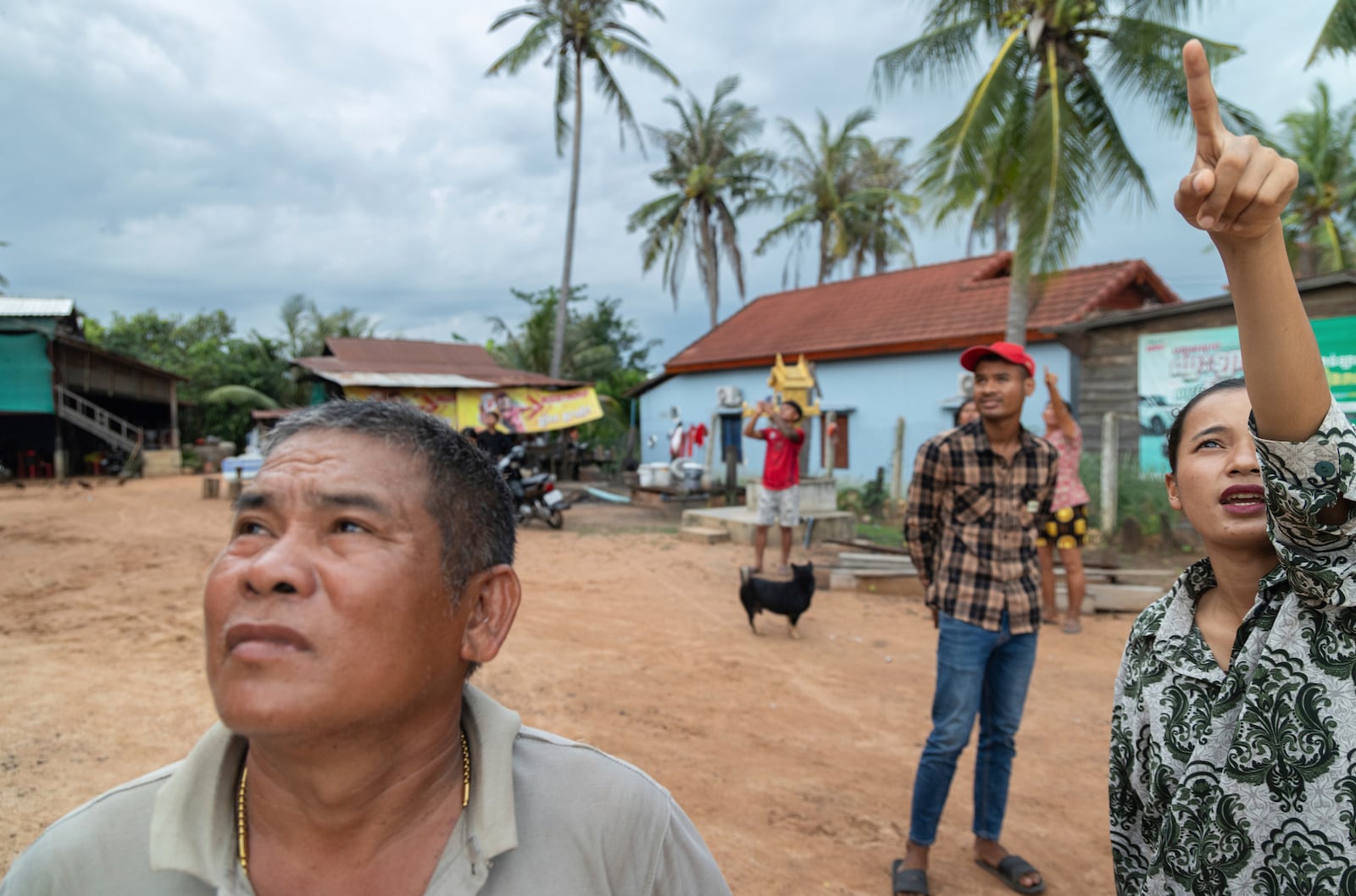 A resident of Samraong, the capital of Cambodia's Oddar Meanchey Province, points to where she sees an aircraft being fired at by Cambodian forces on Friday, July 25, 2025. (AP Photo/Anton L. Delgado)