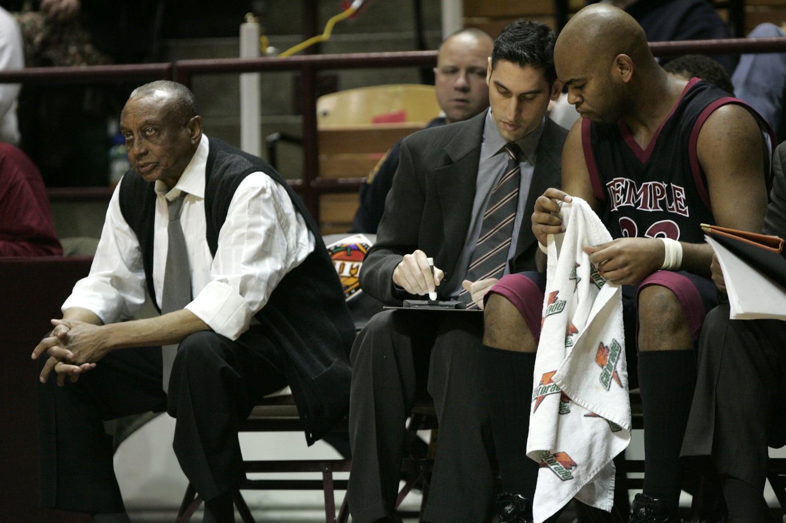 Temple coach John Chaney, left, watches the game as assistant coach Dan Leibovitz, center, talks with Nehemiah Ingram (33) during the Temple-Virginia Tech National Invitational Tournament first-round game at Cassell Coliseum in Blacksburg, Va., Tuesday, March 15, 2005. This is Chaney's first game back following a three-week suspension for sending in a player to commit hard fouls that left Saint Joseph's senior John Bryant with a broken arm.  (AP Photo/Steve Helber)