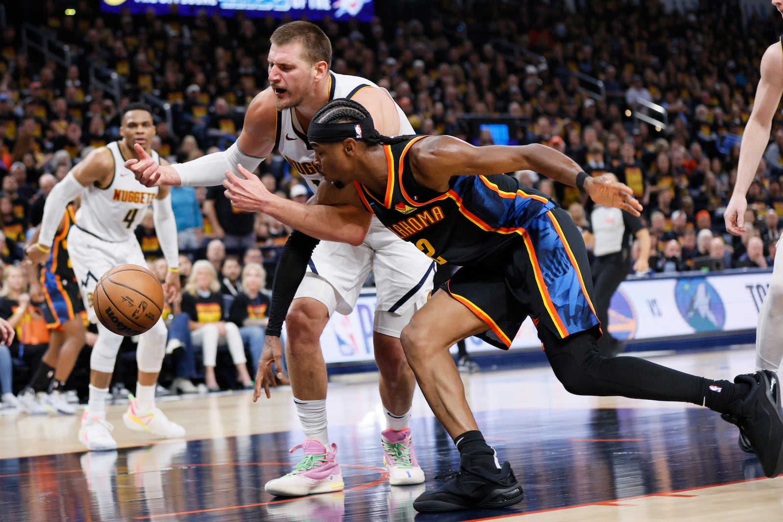 Oklahoma City Thunder's Shai Gilgeous-Alexander (2) and Denver Nuggets' Nikola Jokic, rear, scramble to secure a loose ball in the second half of Game 1 of an NBA basketball second-round playoff series Monday, May 5, 2025, in Oklahoma City. (AP Photo/Nate Billings)