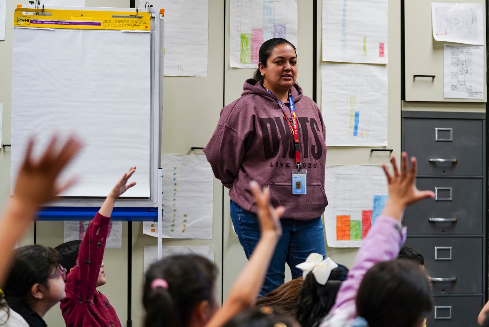 Students raise their hands to be called on by second grade math teacher Johanna Correa at Place Bridge Academy, May 20, 2025, in Denver. (AP Photo/Rebecca Slezak)