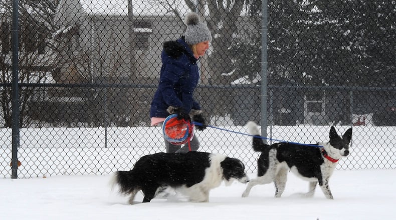 A woman walks her dogs near Shawnee Park in Xenia, on a snowy Wednesday, Feb. 10, 2021. Cold temperatures are expected this weekend, meaning recent snowfall will remain on the ground for an extended period of time. MARSHALL GORBY\STAFF