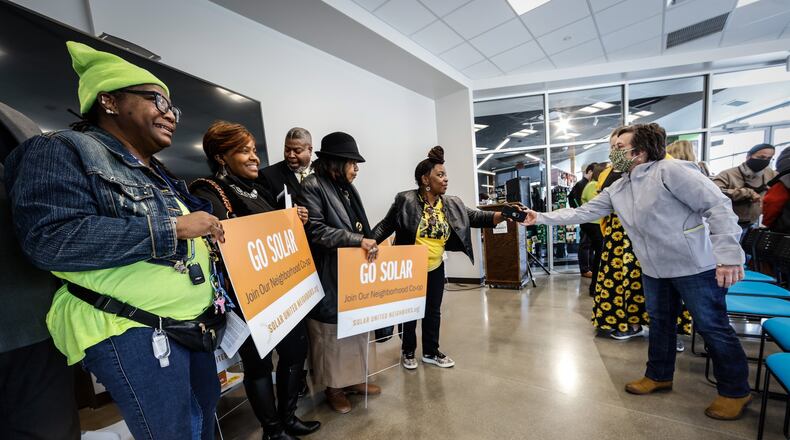 A group from the Dayton NAACP pose for pictures holding go solar signs after a presentation about solar co-op that is available in the Miami Valley. JIM NOELKER/STAFF