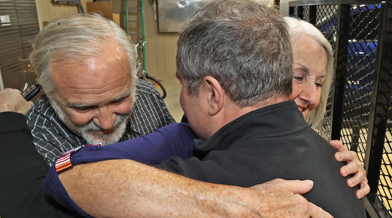 Patrick Driscoll gets a hug by Timothy and Joyce Seymour Friday, April 15, 2022 in his hanger at Andy Barnhart Memorial Airport in New Carlisle. Patrick is receiving the Carnegie Medal for Civilian Heroism for risking his life to save the Seymours from their burning plane after it crashed at the airport. BILL LACKEY/STAFF