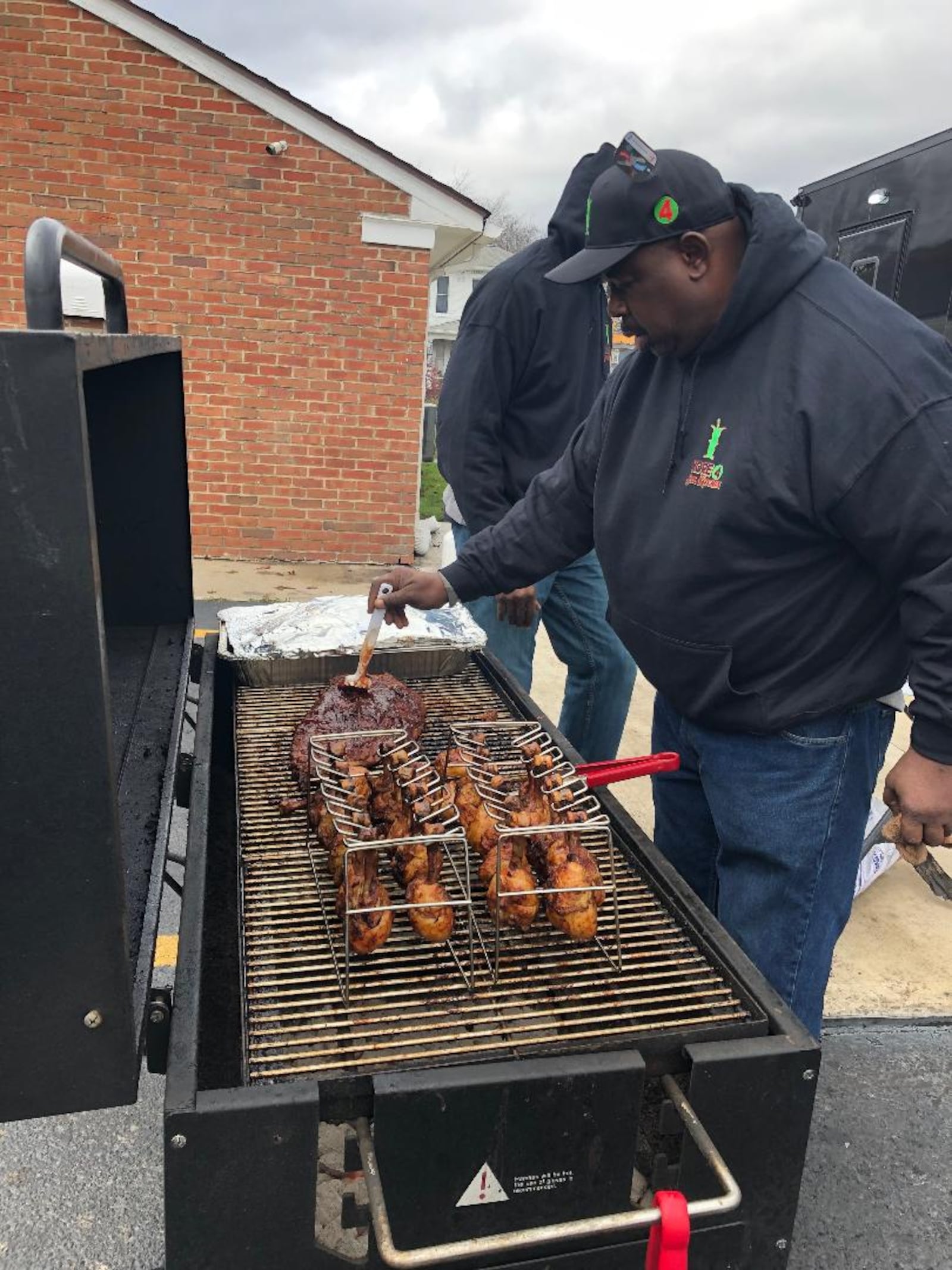 Vernon Bass, one of the four owners of Kore 4 Soul Kitchen, mans the grill cooking chicken and ribs despite strong winds and dropping temperatures during the soft opening of the group's new 28-foot food truck on Saturday.. Photo by Brett Turner