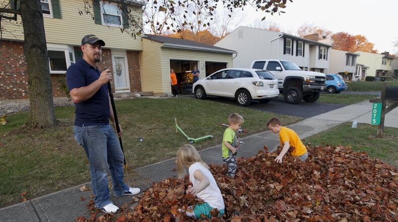 Greg Pekar rakes leaves with his sons Aidan, 10, and Jaxson, 2, along with their neighbor Constance Heeter, 7. Pekar and his wife Amanda, both 28, had no knowledge of the odor befouling the German Village neighborhood in Moraine where they just moved two weeks ago from Cleveland. CHRIS STEWART / STAFF