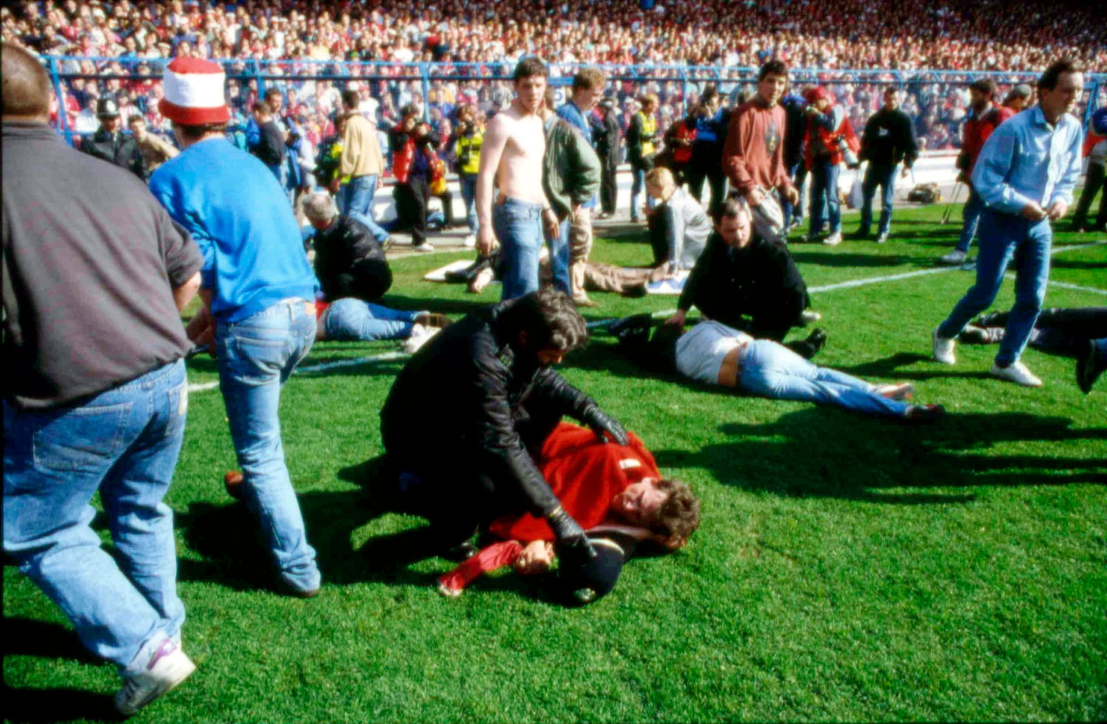 FILE - Stewards and supporters tend and care for wounded supporters on the field at Hillsborough Stadium, in Sheffield, England, April 15, 1989. (AP Photo, File)