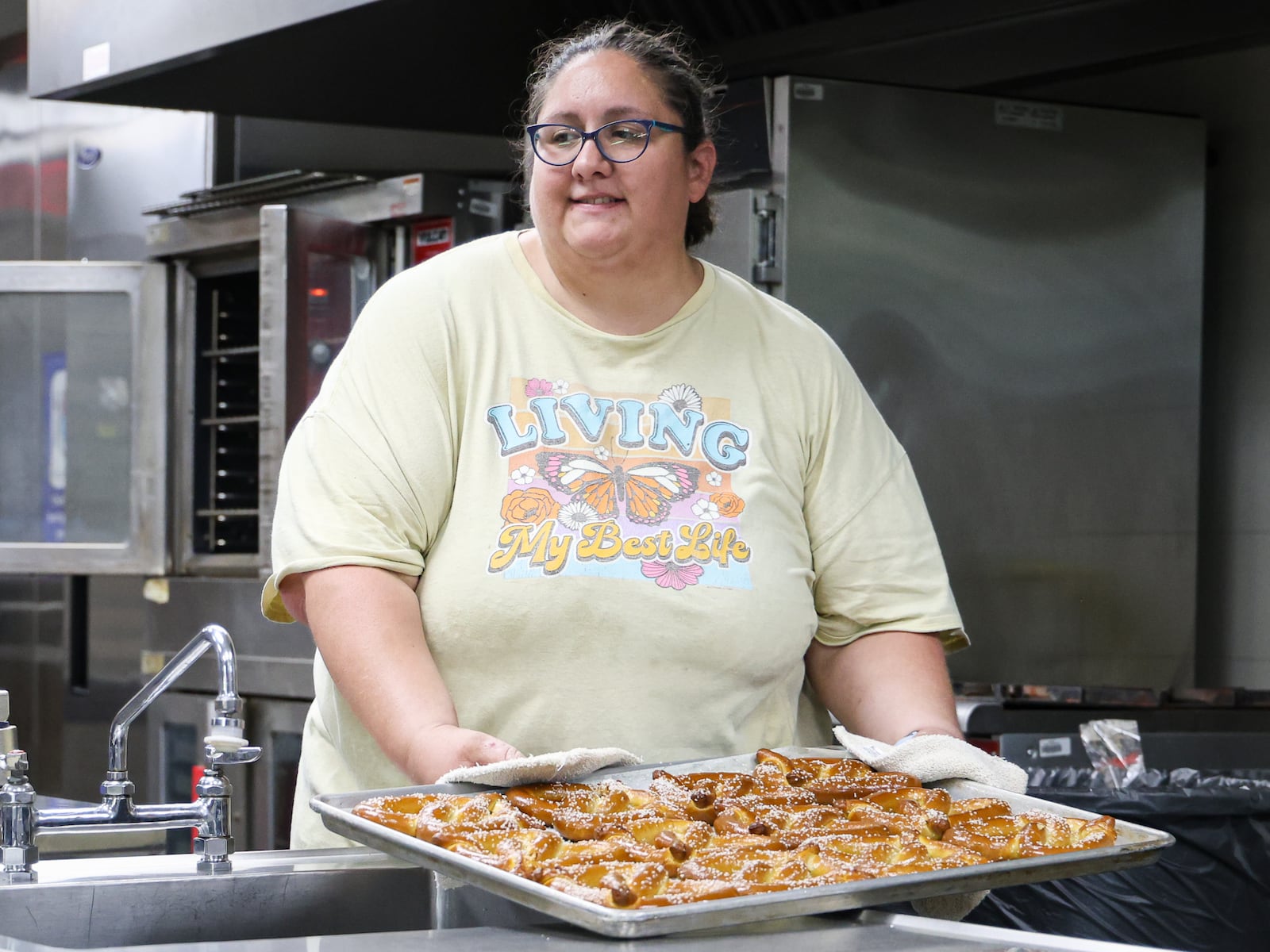 Kelsey Chaney, a food and nutrition supervisor, puts down a tray of pretzels during a summer lunch program organized by Kettering City Schools at Greenmont Elementary on Friday, Aug. 1. It was the final lunch for the program, which ran from June 2 to Friday. BRYANT BILLING / STAFF