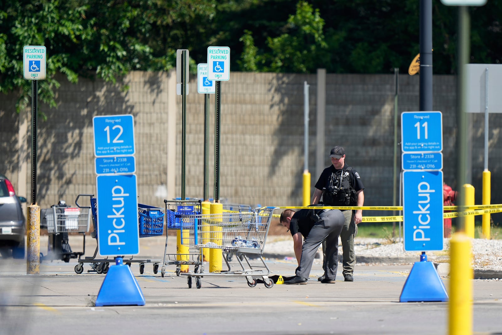 Officers investigate Sunday, July 27, 2025, the scene where 11 people were stabbed at a Walmart in Traverse City, Mich. (AP Photo/Ryan Sun)