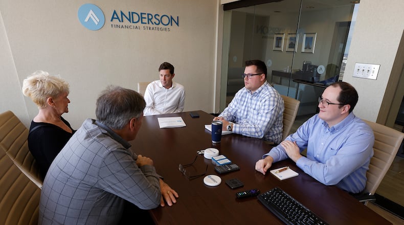 Anderson Financial Strategies President and Chief Wealth Strategist Shon Anderson (center), with Matthew Peck and Collin Lyon (right) talk with a couple in the firm's Dayton office Monday, Dec. 23, 2024, about being financially prepared for retirement. MARSHALL GORBY/STAFF