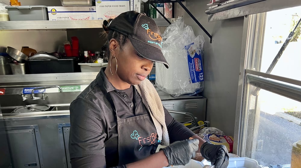 Sha’Ron Burgess prepares fish and chips meals during Sunday's community give back event. AIMEE HANCOCK/STAFF