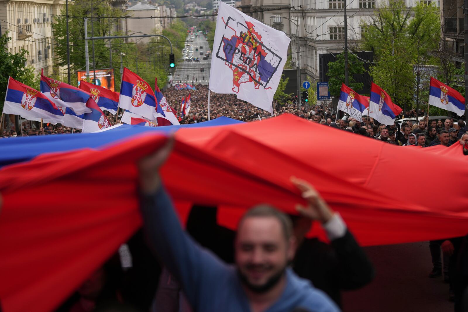 People hold a giant Serbian flag ahead of a big counter-opposition protest rally planned to stage over the weekend in downtown Belgrade, Serbia, Friday, April 11, 2025. (AP Photo/Darko Vojinovic)