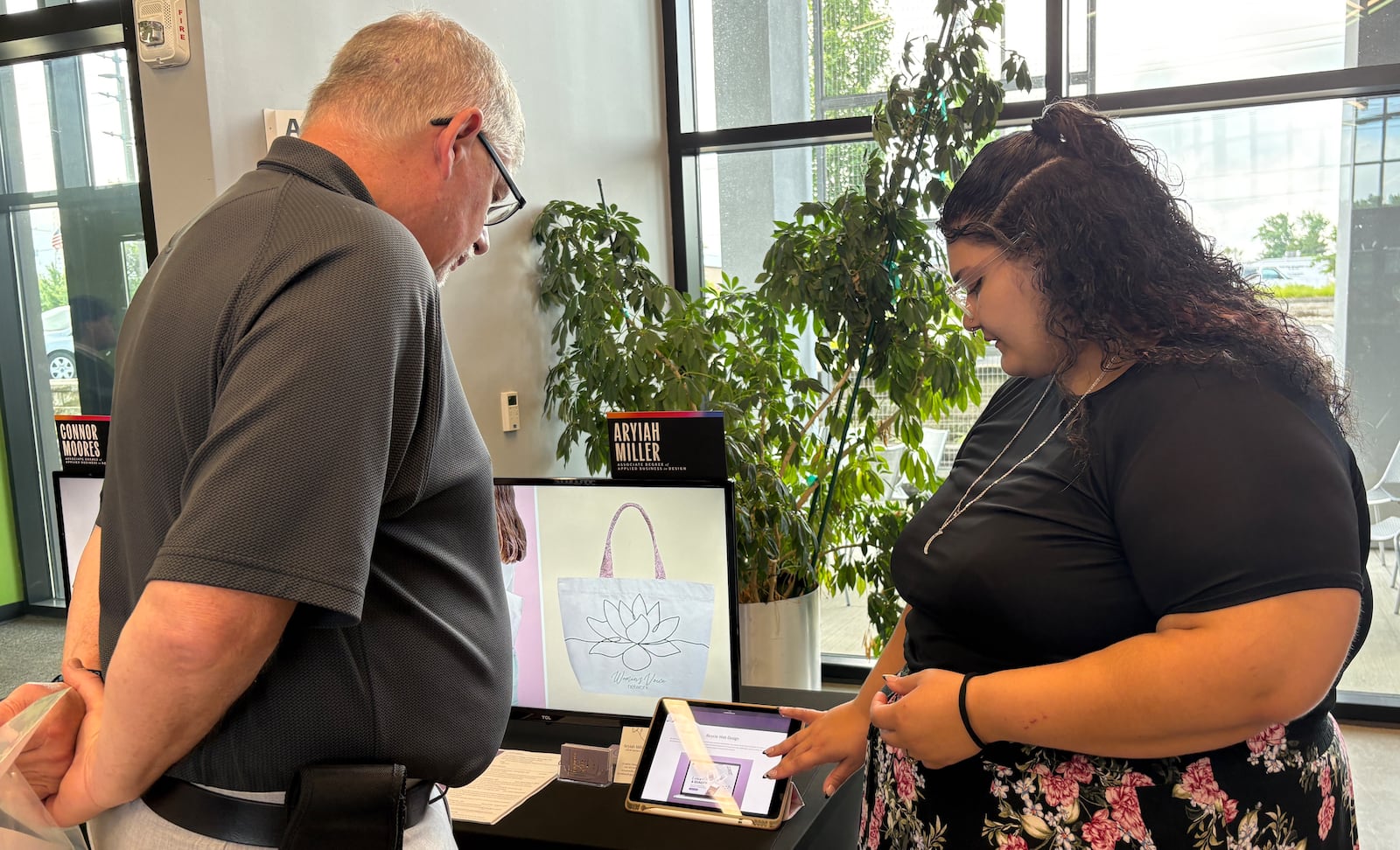 Aryiah Miller, a recent graduate of The Modern College of Design, shares her digital portfolio with Kettering Councilman Bob Scott during the annual "Reveal" showcase Friday, June 6, 2025, at the school in Kettering. JEN BALDUF/STAFF