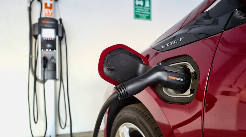 FILE - This Oct. 17, 2018 photo shows a Chevrolet Volt hybrid car charging at a ChargePoint charging station at a parking garage in Los Angeles.  The country, and the world, will need thousands more for drivers to accept vehicles that are powered by batteries alone. But automakers and charging companies are struggling to raise the numbers now because they’re investing before demand arrives. With more than 40 fully electric vehicles on the market in the U.S. or coming within the next three years, however, auto and charging company executives say the demand is on the way.(AP Photo/Richard Vogel, File)