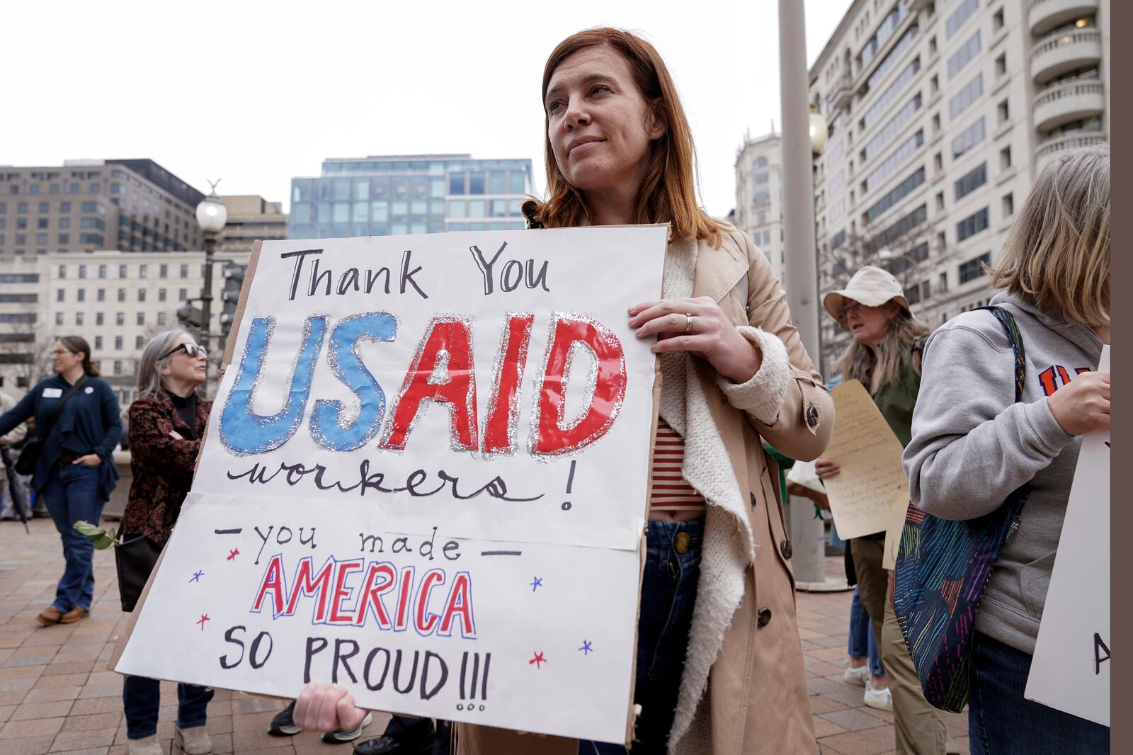 FILE - A person carries a sign in support of the United States Agency for International Development (USAID) workers, as they carry their personal belongings after retrieving them from the USAID's headquarters in Washington, Feb. 27, 2025. (AP Photo/Jose Luis Magana, File)