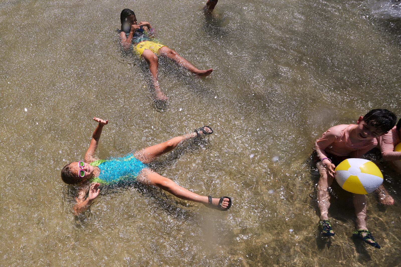With temperatures hovering near 100 degrees, children cool off in the Frog Pond, on Boston Common, Tuesday, June 24, 2025, in Boston. (AP Photo/Charles Krupa)