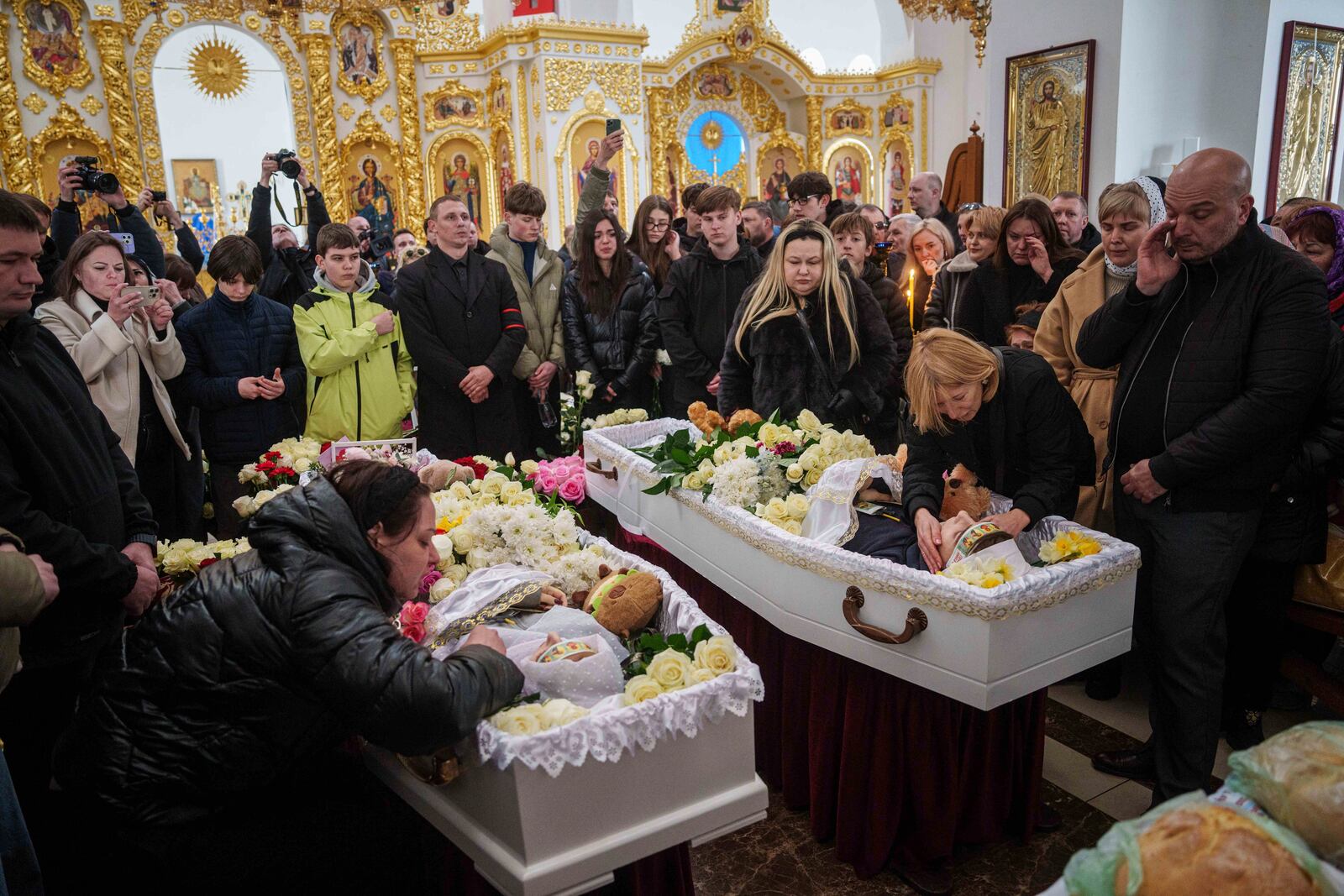 Mothers cry at the coffins of their children Danylo Nikittskyi, 15, right, and Alina Kutsenko, 15, left, killed by a Russian missile, during a funeral ceremony in Kryvyi Rih, Ukraine, April 7, 2025. (AP Photo/Evgeniy Maloletka)