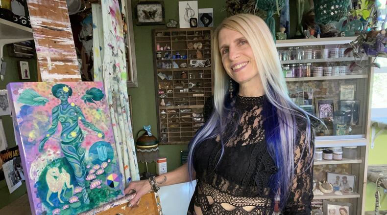 Amy Kollar Anderson stands in her home studio with a painting from her series “Rule Makers/Rule Breakers,” based on the structure of the zodiac constellations. CONTRIBUTED PHOTOS