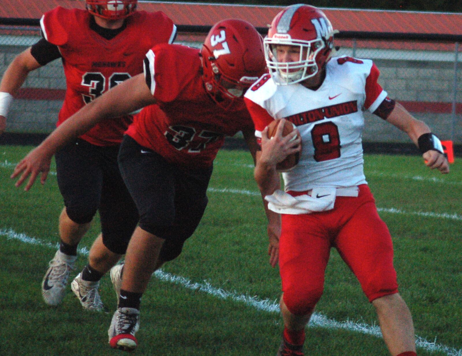 Milton-Union quarterback William Morris tries to avoid Madison’s Tanner Limon on Friday night at Brandenburg Field in Madison Township. The host Mohawks won 46-0. CONTRIBUTED PHOTO BY JOHN CUMMINGS