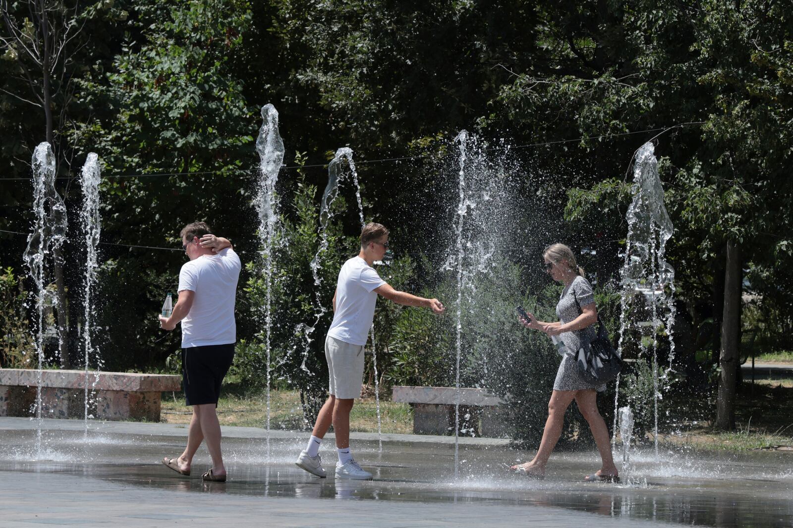 Pedestrians cool themselves in a fountain in central Tirana, Albania, during a heatwave on Friday, July 25, 2025. (AP Photo/Vlasov Sulaj)