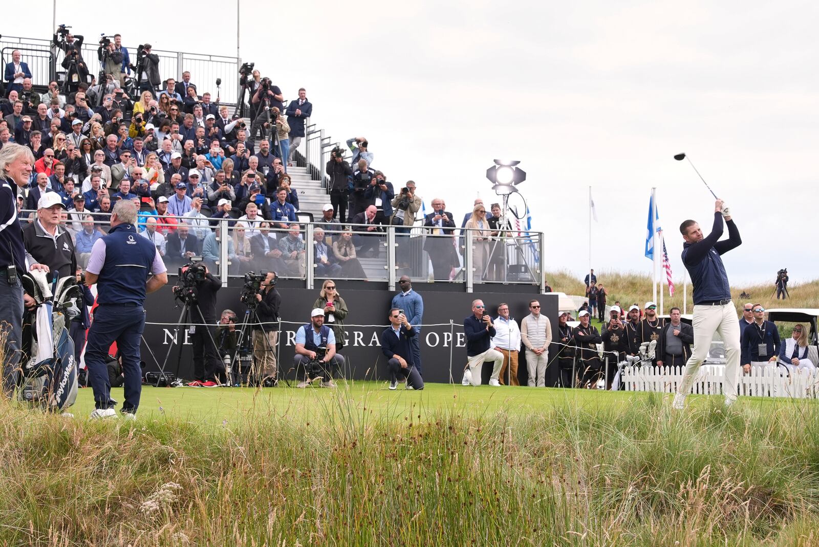 Eric Trump tees off as President Donald Trump, left, stands, during the opening ceremony for the Trump International Golf Links golf course, near Aberdeen, Scotland, Tuesday, July 29, 2025. (AP Photo/Jacquelyn Martin)
