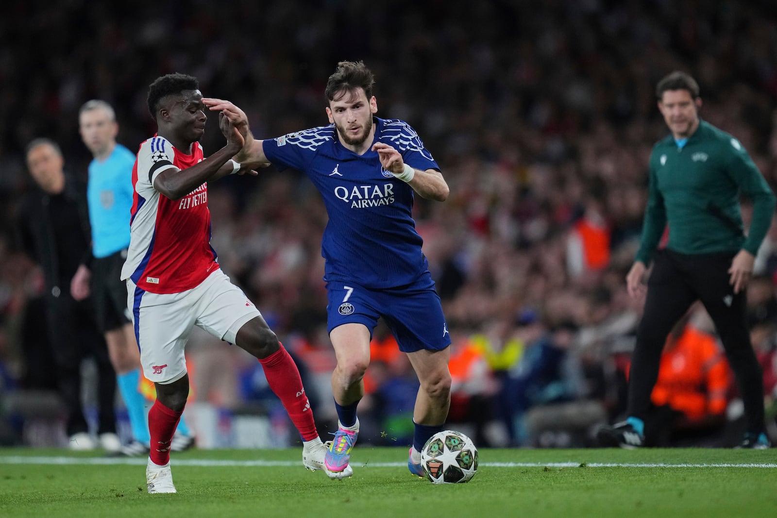 Arsenal's Bukayo Saka, left, fights for the ball with PSG's Khvicha Kvaratskhelia during the Champions League semifinal first leg soccer match between Arsenal and Paris Saint-Germain at Emirates Stadium in London, England, Tuesday, April 29, 2025. (AP Photo/Kirsty Wigglesworth)