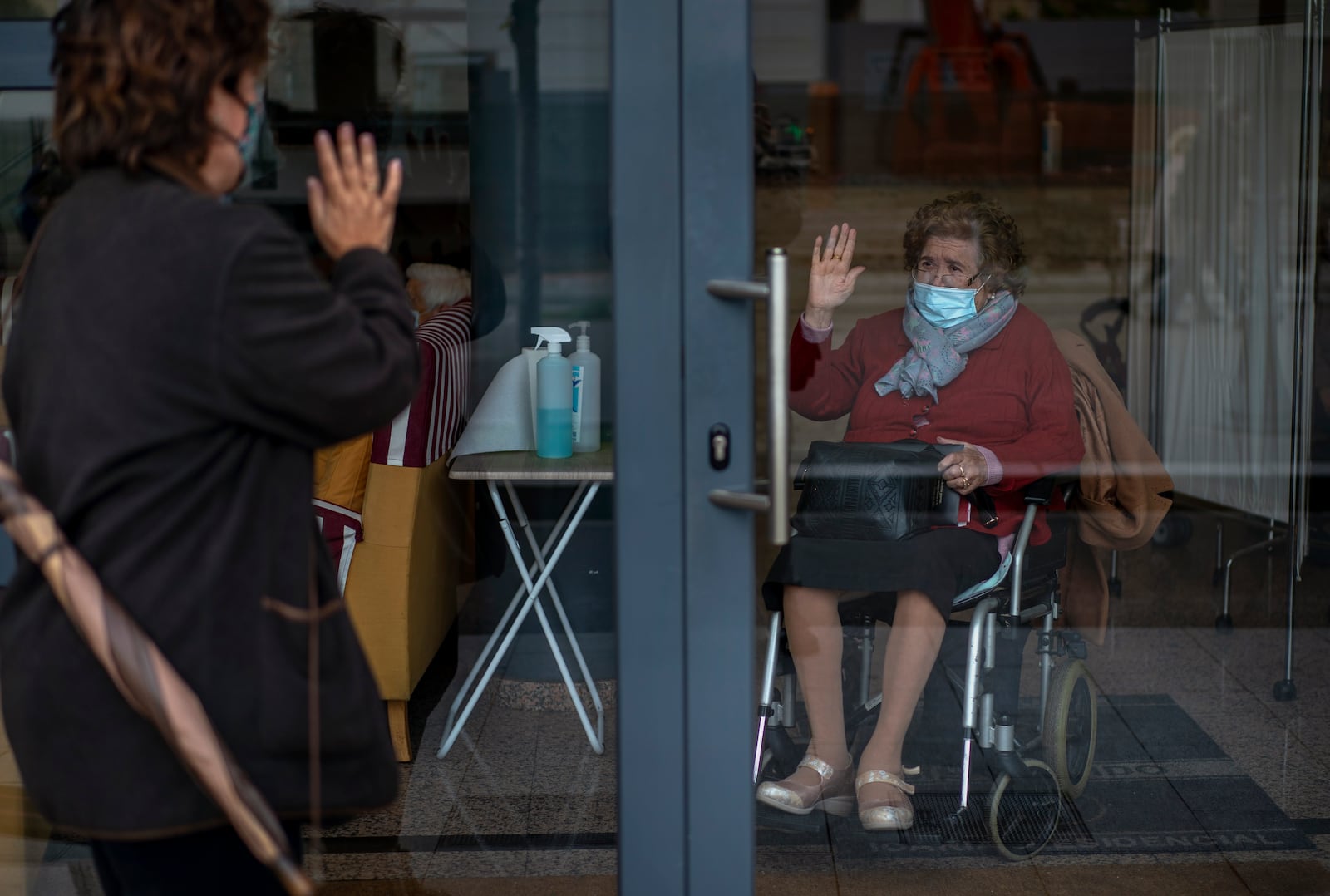 FILE -Angels Trepat, 59, says through a window goodbye to her mother Angelina, 91, after visiting her at the Icaria nursing home in Barcelona, Spain, Friday, Nov. 27, 2020. (AP Photo/Emilio Morenatti, File)