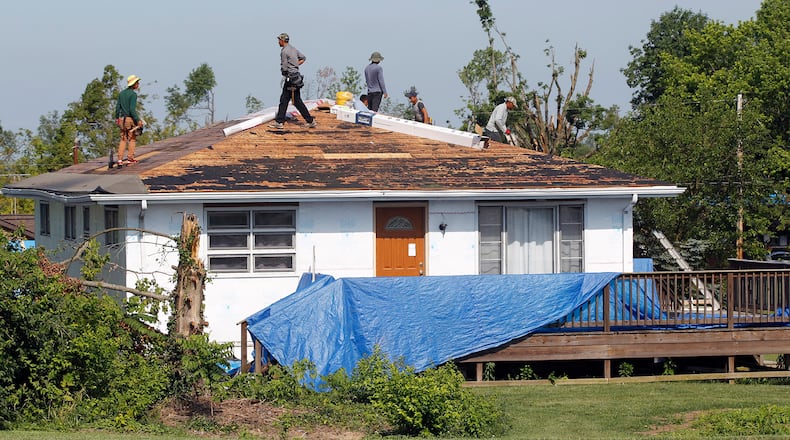 Workers begin the process of reroofing this house on Graham Drive in Beavercreek that was damaged by the Memorail Day tornado. The City of Beavercreek announced on Thursday that it will end pickup of tree debris from residences on July 28. TY GREENLEES / STAFF