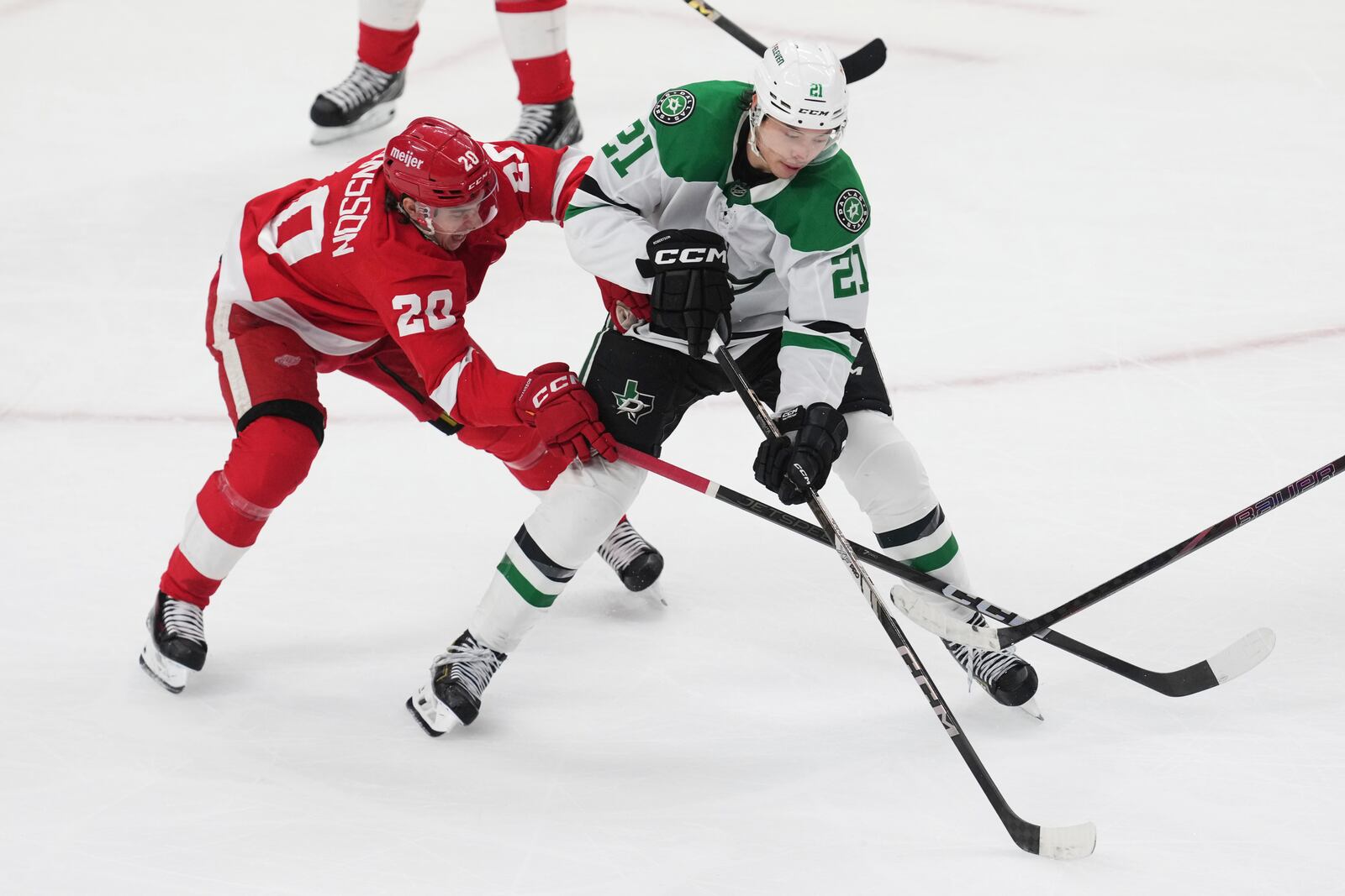 Dallas Stars left wing Jason Robertson (21) protects the puck from Detroit Red Wings defenseman Albert Johansson (20) in the second period of an NHL hockey game Monday, April 14, 2025, in Detroit. (AP Photo/Paul Sancya)