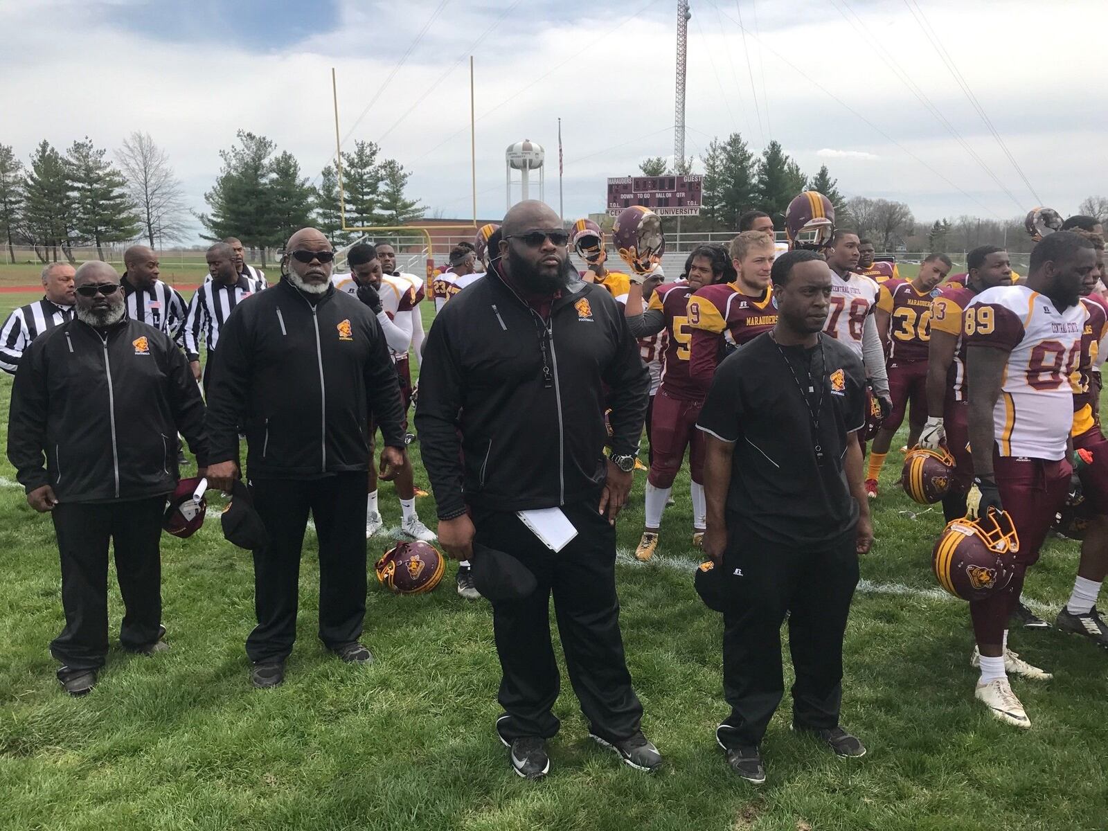 Former Chaminade Julienne standout Brandon McKinney (third from left), stands as Central State band plays alma mater following Sp[ring Game Saturday. McKinney, a longtime player in the NFL, is a first-year assistant coach at Central State. Tom Archdeacon/STAFF