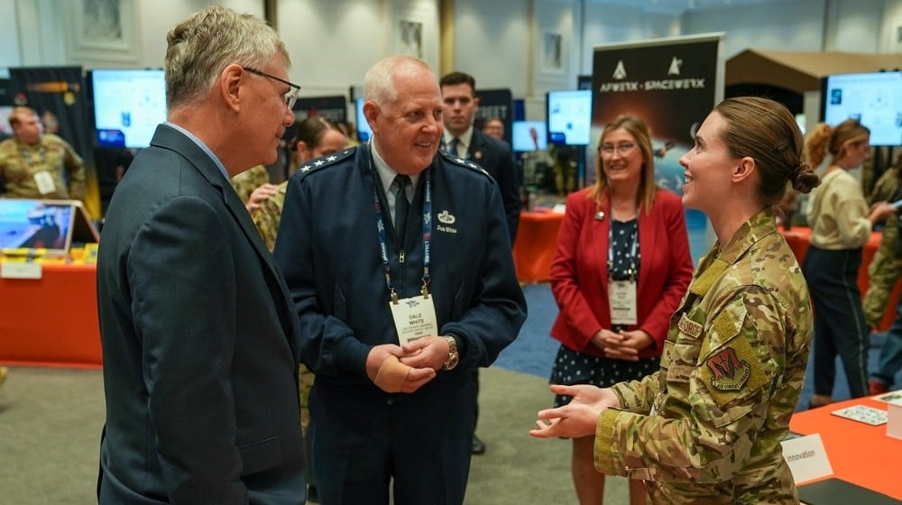 Senior Airman Erika Gustafson, AFWERX Spark (right), briefs Troy Meink, secretary of the Air Force (left), and Lt. Gen. Dale White (middle), Office of the Assistant Secretary of the Air Force for Acquisition, Technology, and Logistics military deputy, during the Air, Space and Cyber Conference in National Harbor, Md., on Sept. 24, 2025. Air Force photo by Matthew Clouse.