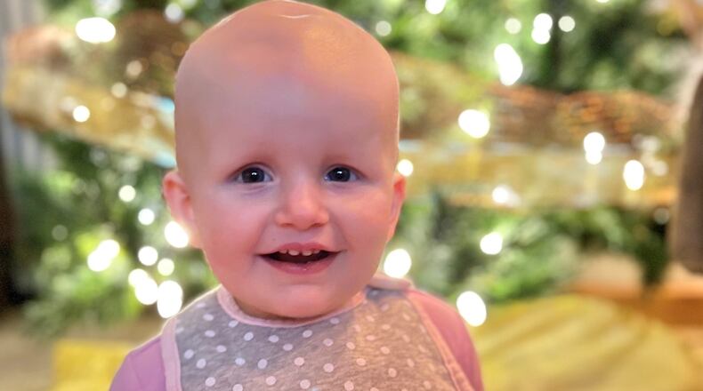Kayleigh Truster, a pediatric oncology patient at Dayton Children's Hospital, smiles in front of a Christmas tree. Kayleigh, who is now two years old, was diagnosed with infantile glioblastoma when she was nine months old. CONTRIBUTED