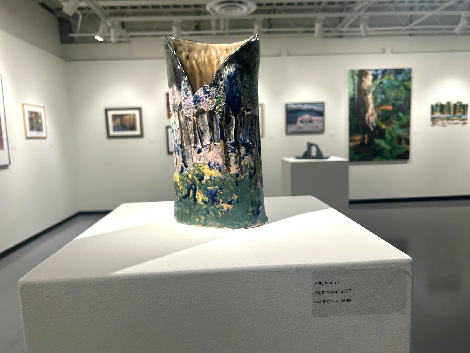 'Night wood' by Amy Ivanoff, midrange porcelain, 2023. It is placed on a pedestal as a foreground object to Ryan Kerr’s oil painting, “Day One on the Long Trail”, seen on the wall. CONTRIBUTED/HANNAH KASPER