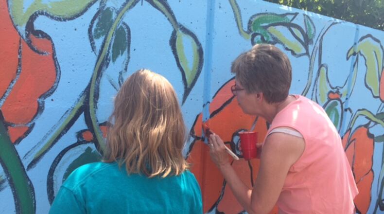 South Park residents and local artists help paint a mural Saturday, June 17, 2017, on the corner of Wayne Avenue and Hickory Street in Dayton.