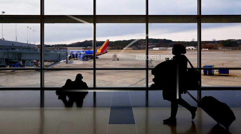 FILE- IN this Dec. 19, 2016, file photo, travelers walk through a the airport to board an airplane during holiday travel at the Birmingham-Shuttlesworth International Airport in Birmingham, Ala. Major airlines including American Airlines, JetBlue, Southwest Airlines and United Airlines integrate buy-now-pay-later concepts into their online booking. (AP Photo/Brynn Anderson, File)