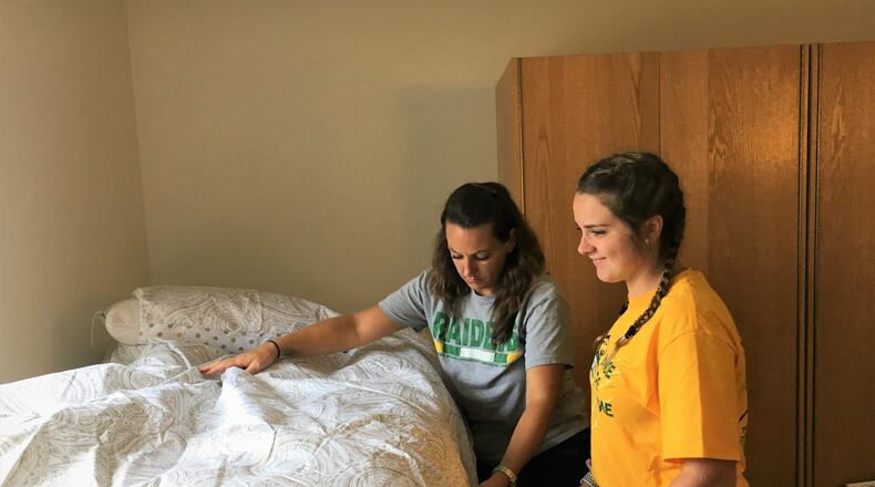 Victoria Hawk and her mom Kim work on making the bed in her dorm room at Wright State University. STAFF PHOTO / HOLLY SHIVELY
