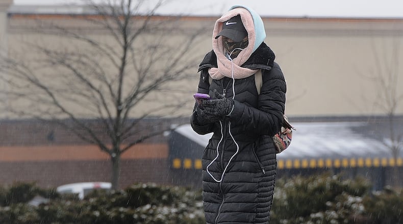 A woman bundles up against the cold as she walks along Old Troy Pike in Huber Heights, Monday, Jan. 25, 2021. A Winter Weather Advisory has been issued as freezing rain and a wintry mix move into the area. MARSHALL GORBY\STAFF