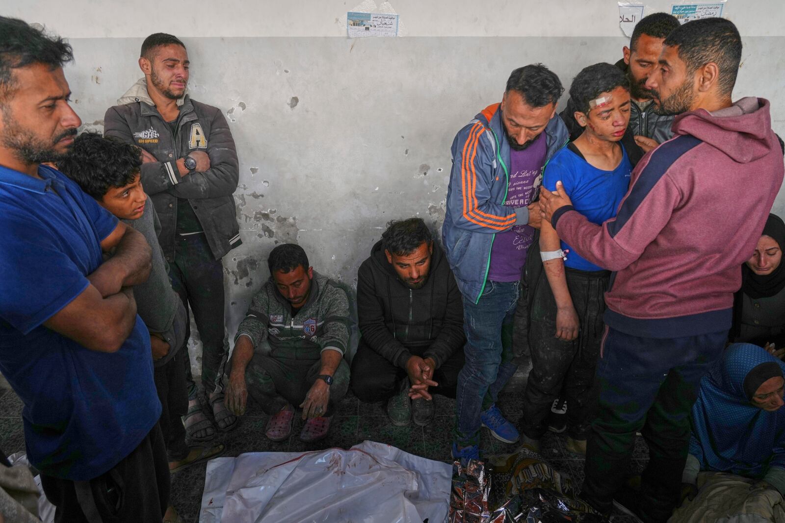 Mahmoud Al-Sayfi, 13, right with blue shirt, is comforted by relatives as he mourns both his parents killed during an Israeli army strike before their burial at the Baptist hospital in Gaza City, Monday, March 24, 2025.(AP Photo/Jehad Alshrafi)