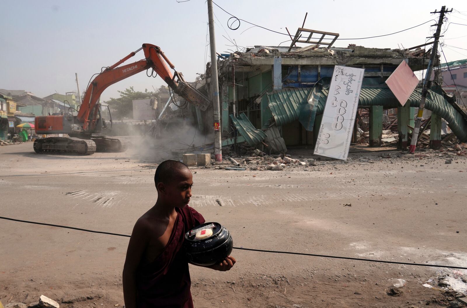 A Buddhist novice monk walks past damaged buildings at a market, after one month of the strong earthquake in Naypyitaw, Myanmar, Monday, April 28, 2025. (AP Photo/Aung Shine Oo)