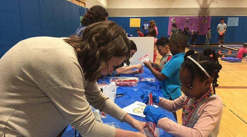 Christina Davis, student research assistant with the 711th Human Performance Wing, Air Force Research Laboratory, assists a student with identifying plant cell structures by extracting visible DNA from crushed and strained strawberries during STEMfest 3.14 at the Youth Center, Wright-Patterson Air Force Base, March 14. (Skywrighter photo/Amy Rollins)