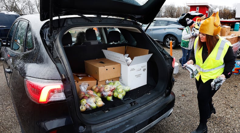 Kenzie Hunter, wearing her turkey hat helps load food into vehicles Thursday, Nov. 21, 2024 at the annual Food Bank food distribution before Thanksgiving at the Dixie Twin Drive-In Theater. MARSHALL GORBY\STAFF