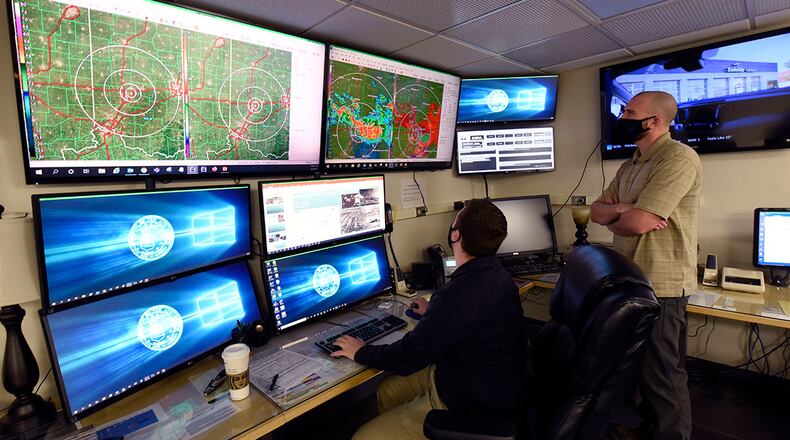 Air Force contractors Ryan Balding, left, and Zach Grandin, 88th Operations Support Squadron weather technicians, discuss past weather systems in the Base Weather Station at Wright-Patterson Air Force Base, Ohio on March 2, 2021. The Base Weather Station operates with ten contactors, around the clock and supports the aviation mission through briefs, observations and forecasts, and the resource protection mission through watches, warnings and advisories. (U.S. Air Force photo by Ty Greenlees)