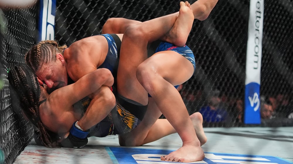 Kayla Harrison, right, grapples with Julianna Peña during the second round of a women's bantamweight bout at the UFC 316 mixed martial arts event Sunday, June 8, 2025 in Newark, N.J. (AP Photo/Frank Franklin II)